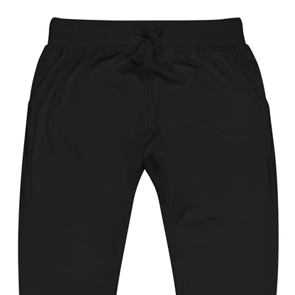 One Step at a Time Joggers in Black — close-up of the embroidered One Step at a Time logo at the left thigh
