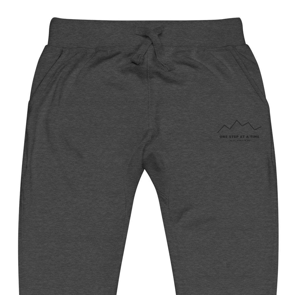 One Step at a Time Joggers in Charcoal Heather — close-up of the embroidered One Step at a Time logo at the left thigh