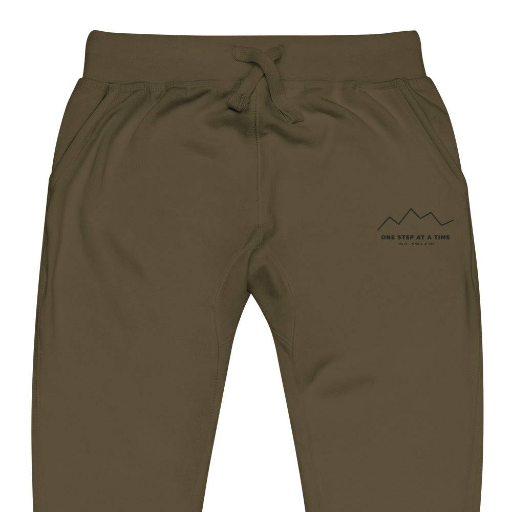 One Step at a Time Joggers in Military Green — close-up of the embroidered One Step at a Time logo at the left thigh
