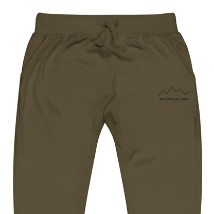 One Step at a Time Joggers in Military Green — close-up of the embroidered One Step at a Time logo at the left thigh