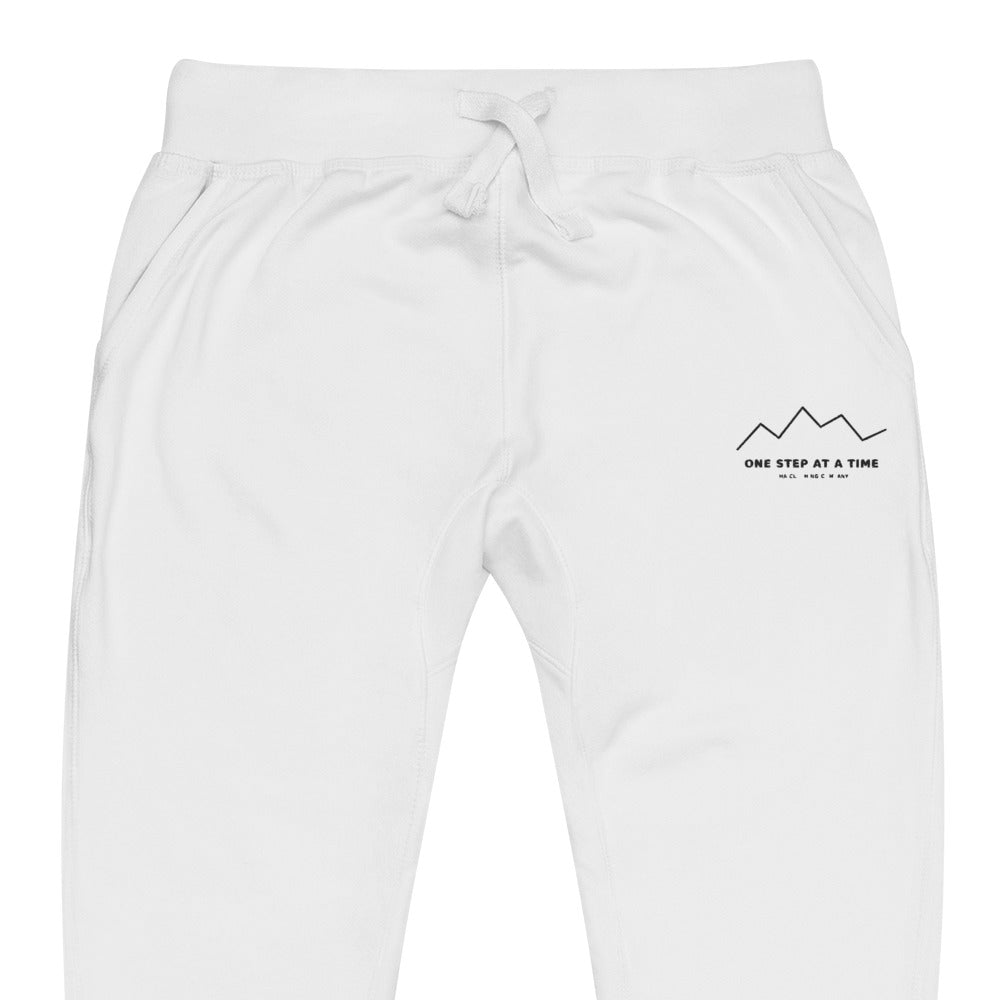 One Step at a Time Joggers in White — close-up of the embroidered One Step at a Time logo at the left thigh